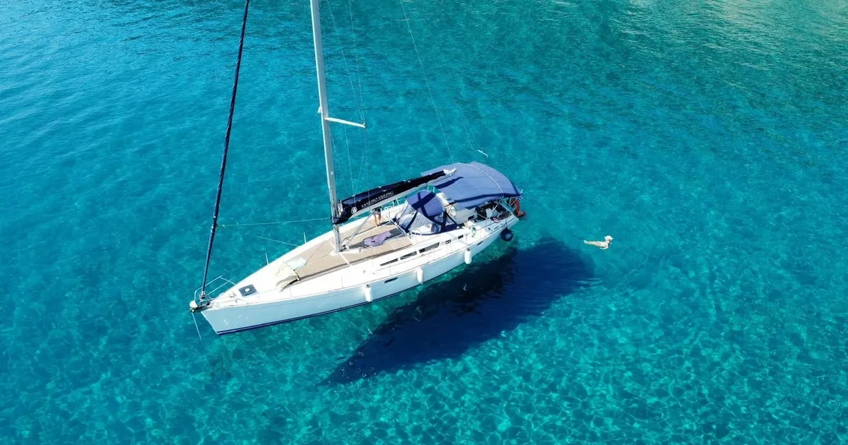 Small sailing yacht heeling gently across blue Aegean water on a small-group sailing trip from Naxos to the Small Cyclades
